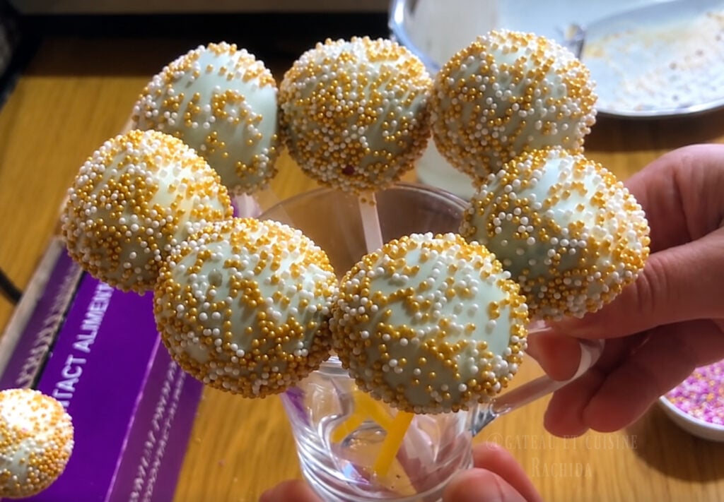 White chocolate coated cake pops decorated with colorful sprinkles on stick