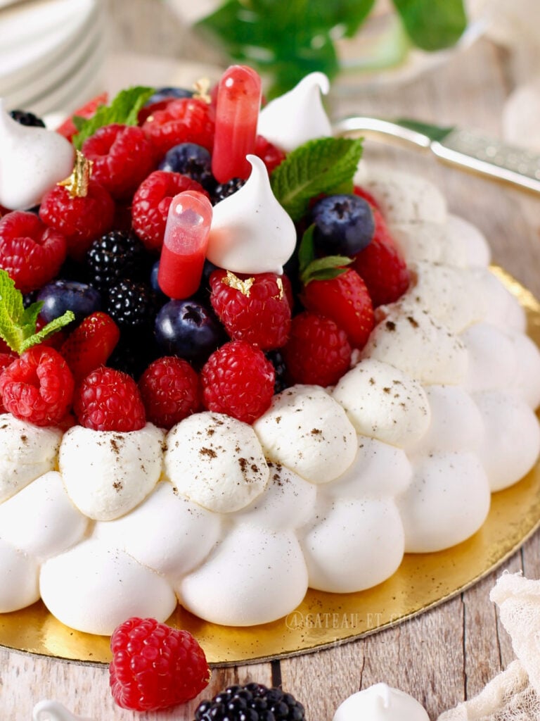 pavlova garnie de chantilly légère et de fruits rouge décorée de petites meringues et de menthe